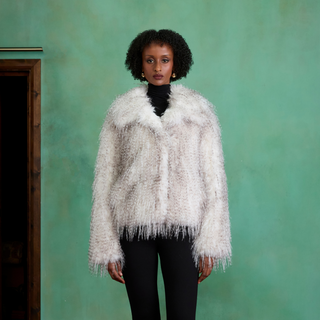 Woman wearing a white fluffy fur jacket against a green background